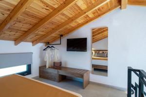 a living room with a television and a bed at Arroyo Suites Kalamitsi in Kalamitsi