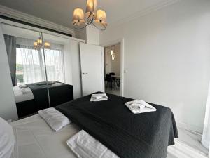 a bedroom with a black bed with two towels on it at Promenada Gwiazd 14 by Baltic Home in Międzyzdroje