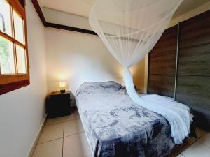 a bedroom with a bed with a mosquito net at La Villa Césaire au cœur de la nature luxuriante ! in Vieux-Habitants