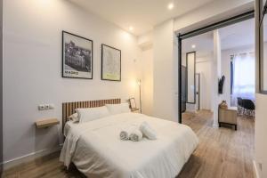 1 dormitorio con 1 cama blanca y 2 toallas en MyHouseSpain - Acogedor piso cerca de Atocha II, en Madrid