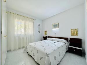a white bedroom with a bed and a window at Ambient CostaBravaSi in Platja d'Aro