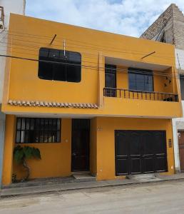 a yellow building with black doors and a balcony at Yellow House in Huanchaco