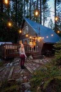 a woman standing in front of a small house at Retro A-Frame Cabin - Firepit & Fireplace in Skykomish