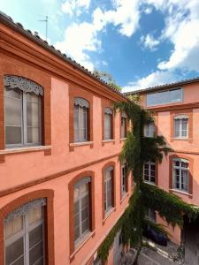 un grand bâtiment en brique orange avec des fenêtres et des vignes dans l'établissement Superbe duplex climatisé place St Etienne, parking, à Toulouse