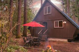 a red umbrella and a table and chairs in front of a cabin at Retro A-Frame Cabin - Firepit & Fireplace in Skykomish