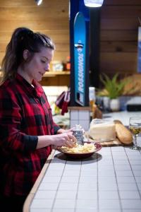 kobieta stojąca przy ladzie z talerzem jedzenia w obiekcie Retro A-Frame Cabin - Firepit & Fireplace w mieście Skykomish