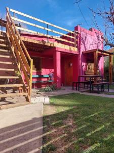una casa rosa con una mesa de picnic delante de ella en Hostel Ruta76 en Sierra de la Ventana