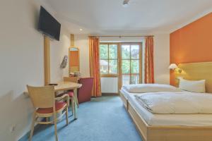 エタールにあるAlphotel Ettalのベッドとデスクが備わるホテルルームです。