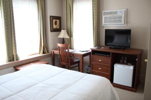 1 dormitorio con 1 cama y escritorio con TV en The Sonata Inn, en Charlottetown