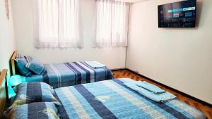 1 dormitorio con 2 camas y TV en la pared en ACOGEDOR DEPA SAN MIGUEL, CON INTERNET, en Lima