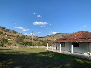 a white building with a fence and a grass field at Recanto Bellini's in Barreira