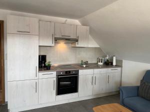 a kitchen with white cabinets and a stove top oven at Ferienhaus Ankerweg an der Seehundstation in Norddeich