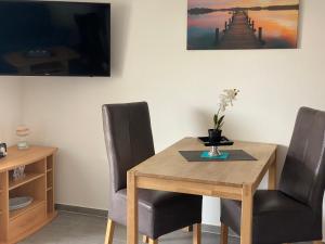 a wooden table with two chairs and a vase with flowers on it at Ferienhaus Ankerweg an der Seehundstation in Norddeich