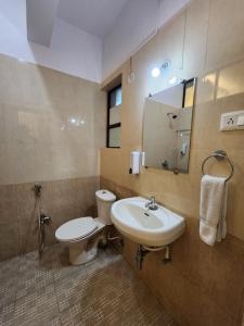 a bathroom with a sink and a toilet and a mirror at All Seasons Guest House I Rooms & Dorms in Madgaon