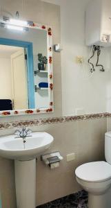 a bathroom with a sink and a toilet and a mirror at Apartamento Playa Grande in Tías