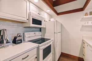 a kitchen with white cabinets and a white refrigerator at Kiahuna Plantation Renovated 1br, Private Lanai, AC 411 in Koloa