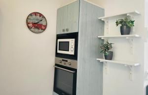 a kitchen with a microwave and a clock on the wall at Apartamento Playa Grande in Tías