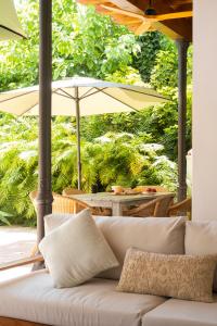 Villa Elisa في مالقة: أريكة بيضاء تجلس على شرفة مع مظلة