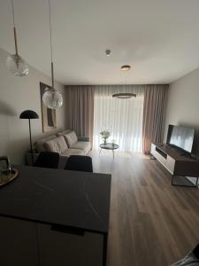 a living room with a couch and a table and a television at Obelų namai, self check-in, free parking in Klaipėda