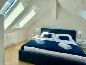ein großes blaues Bett in einem weißen Zimmer mit Oberlichtern in der Unterkunft Apartmány Harmony Liptov in Liptovský Mikuláš