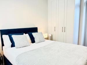 a white bed with blue and white pillows on it at Modern Apartment at Temple Bar with River View in Dublin