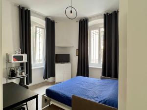 a bedroom with a blue bed and a desk and windows at Casa Genova 1/2/3 in Turin