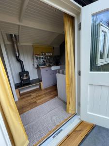 an open door of a tiny house with a kitchen at The Old Post Office - Luxurious Shepherds Hut 'Far From the Madding Crowd' based in rural Dorset. in Todber