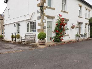 a white building with a bench and a christmas tree at Dales Cottage in Grassington