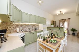 una cocina con armarios verdes, mesa y sillas en Villa Val-Gio, en Ermoupoli