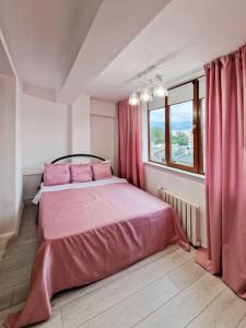 een slaapkamer met een roze bed en een raam bij Стильная квартира в центре in Alma-Ata