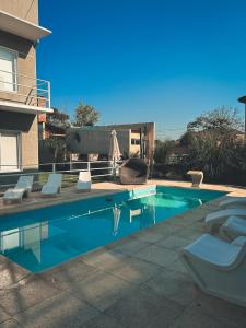 a swimming pool with lounge chairs next to a house at Buenos Vientos Complejo - Termas Chajarí in Chajarí