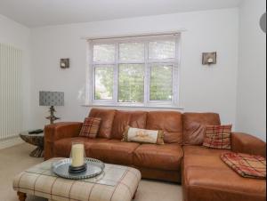 a living room with a brown leather couch and a window at Griff Lodge in Harome
