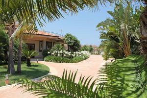 a house with a garden with white flowers and trees at Hotel Santa Chiara in Capo Vaticano