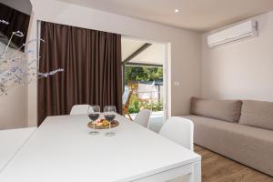 a white dining room with a white table and glasses of wine at Mobile House KASTANJOLA in Biograd na Moru