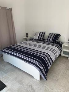 ein Bett mit einer schwarzen und weißen Bettdecke in einem Schlafzimmer in der Unterkunft Terre de Lumière 3 in Nyons