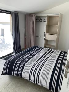 ein Schlafzimmer mit einem gestreiften Bett und einem Fenster in der Unterkunft Terre de Lumière 3 in Nyons