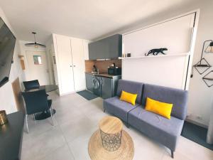 ein Wohnzimmer mit einem blauen Sofa und gelben Kissen in der Unterkunft Ginkgo Studio - piscine, proche de la mer, Golf, WIFI in Mandelieu-la-Napoule