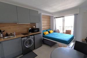 eine kleine Küche mit einem Bett und einer Waschmaschine in der Unterkunft Ginkgo Studio - piscine, proche de la mer, Golf, WIFI in Mandelieu-la-Napoule