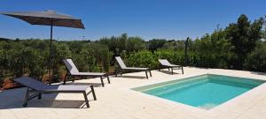 - un groupe de chaises et un parasol à côté de la piscine dans l'établissement Fogliantica Azienda Agrituristica, à Ceglie Messapica