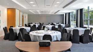 a conference room with tables and chairs and tablesktop at Holiday Inn Express Leigh - Sports Village by IHG in Leigh