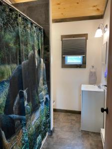 a bathroom with a bear shower curtain next to a sink at Lily Pad Cabin 