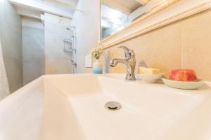 La salle de bains est pourvue d'un lavabo blanc, d'un miroir et d'une pomme. dans l'établissement Casa Taila, à Ruffano