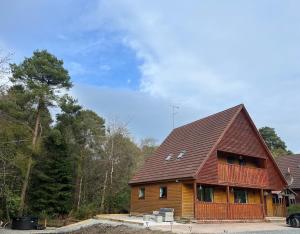 a large wooden house with a brown roof at Cosy Lakeside Chalet With Option to add Private Hot Tub & Boat in Duneena
