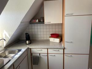 una pequeña cocina con armarios blancos y fregadero en Ferienwohnung Röpersberg en Ratzeburg