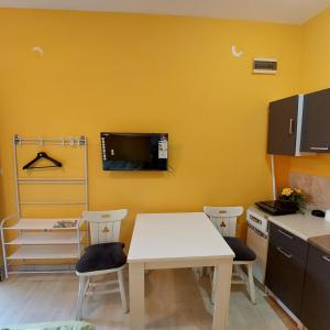 een keuken met een tafel en stoelen en een tv aan de muur bij Apartman Lara in Kruševac