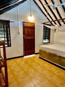 1 dormitorio con 1 cama y puerta de madera en Milele Lodge, en Michamvi