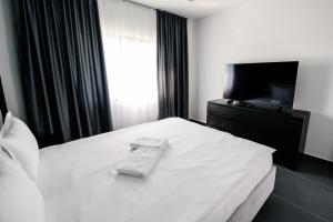 a bedroom with a white bed and a television at Concept Villa in Livezeni