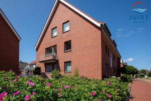 a brick building with pink flowers in front of it at Haus Hamburg 181 Wohnung 1 in Juist