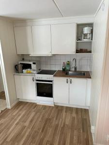 a small kitchen with white cabinets and a wooden floor at Apartment in Lindvallen in Sälen