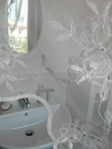 uma casa de banho branca com um lavatório e um espelho em Ildi's Guest House em Seriate